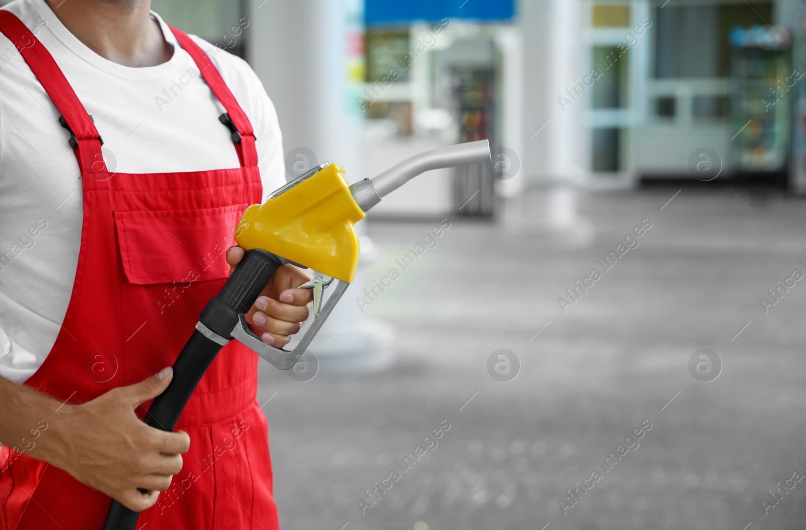 Photo of Worker with fuel pump nozzle at modern gas station, closeup