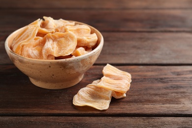 Photo of Delicious dried jackfruit slices on wooden table, closeup. Space for text