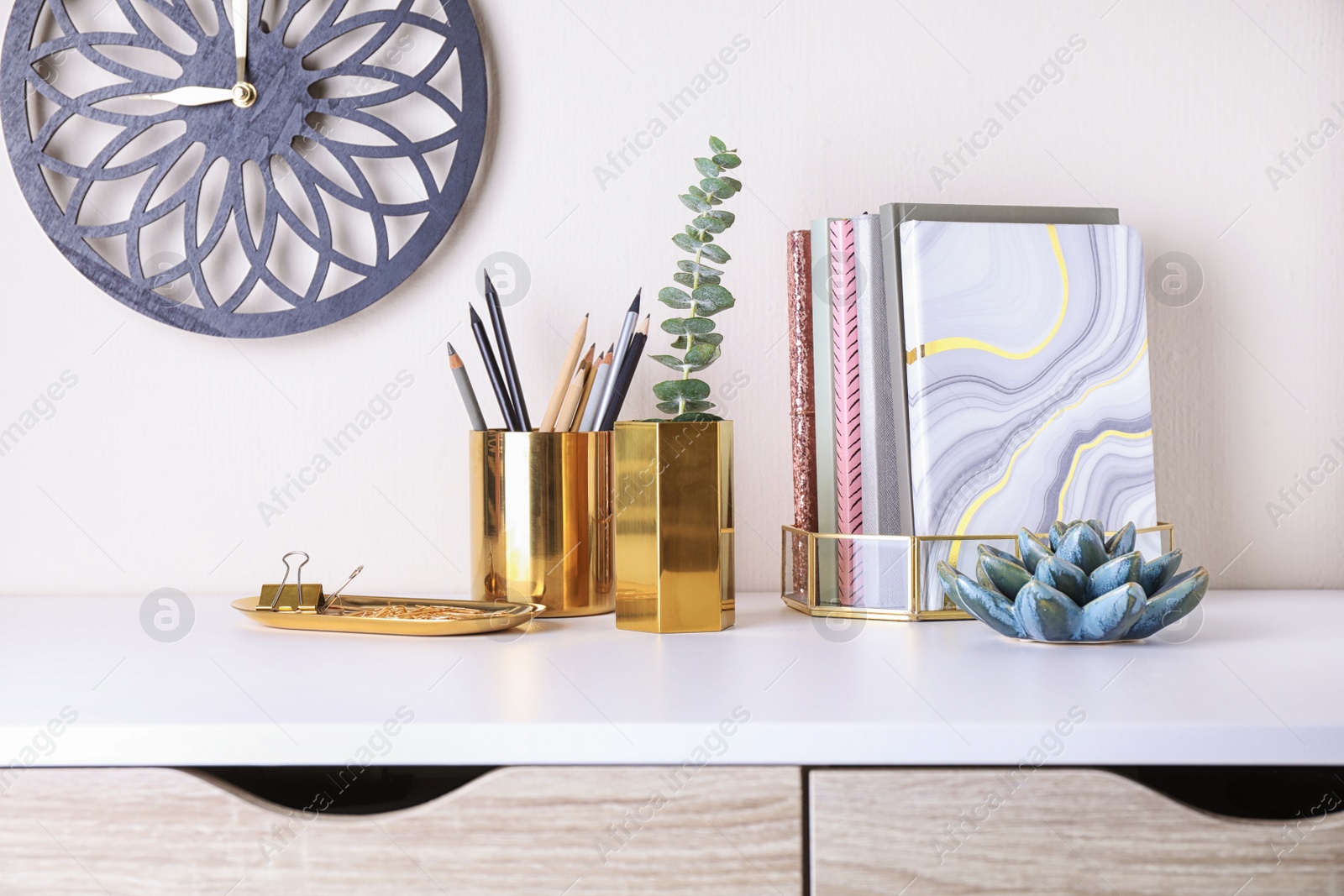 Photo of Stylish holder for stationery with office supplies and decorative elements on white table against light background