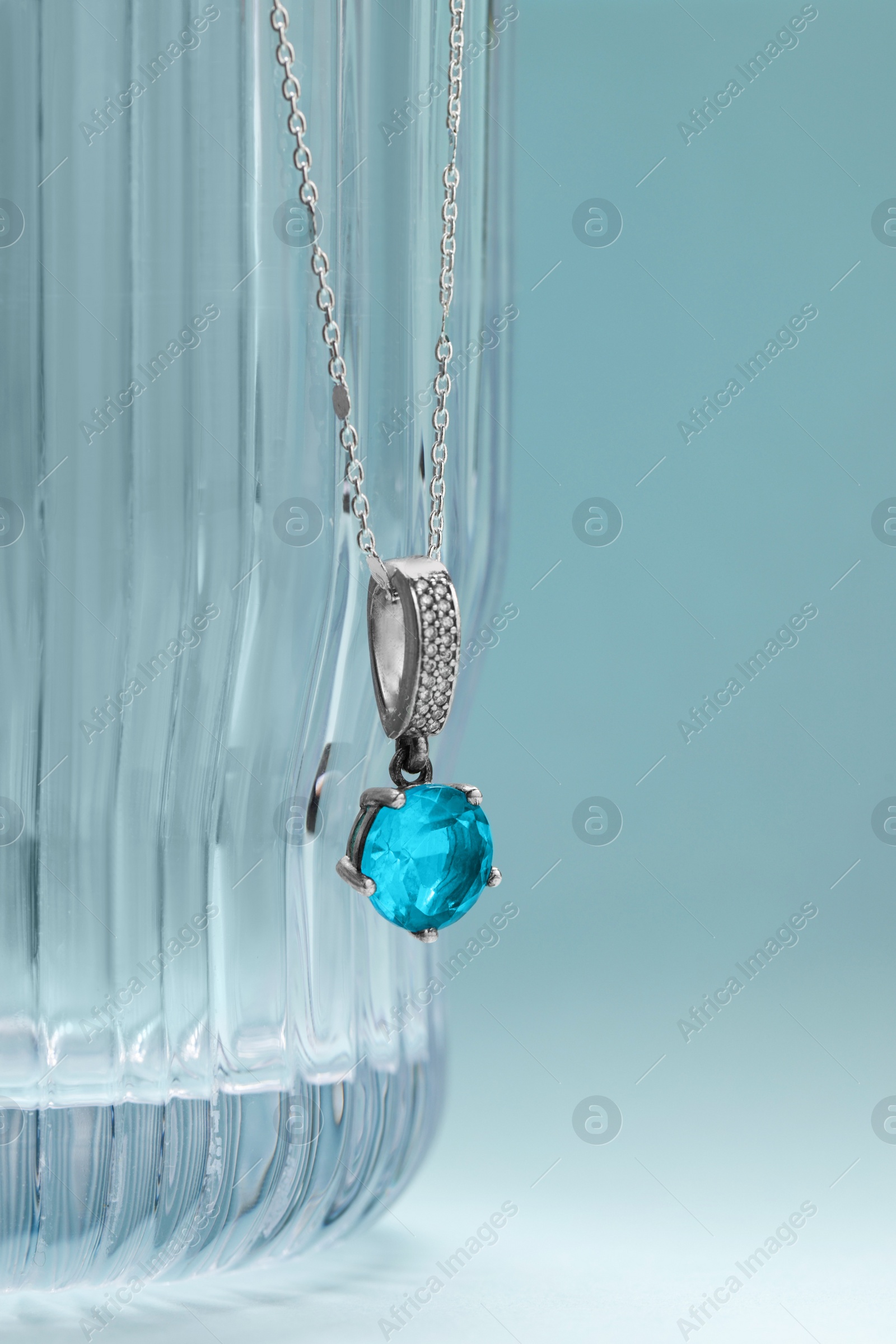 Photo of Beautiful necklace with gemstone on light blue background. Luxury jewelry