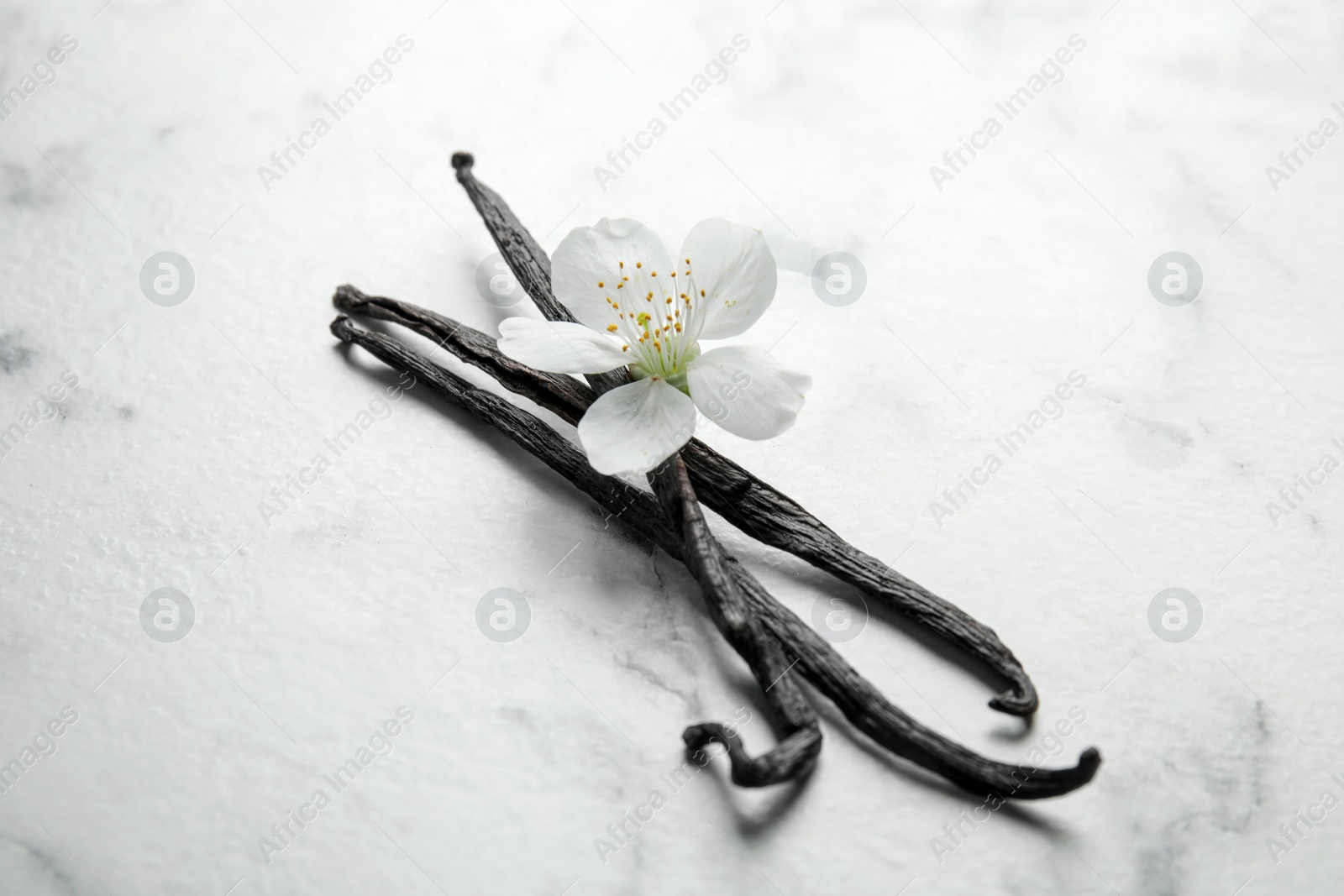 Photo of Aromatic vanilla sticks and flower on marble background