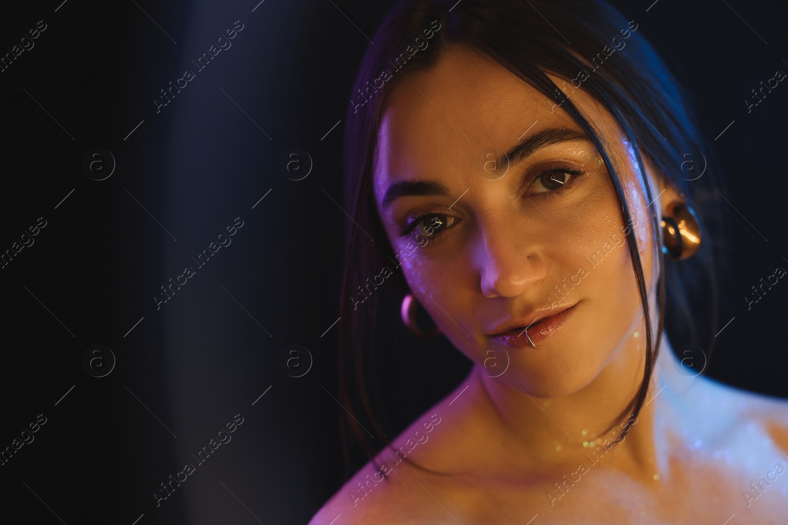 Photo of Portrait of beautiful woman on dark background in neon lights, view through ring lamp