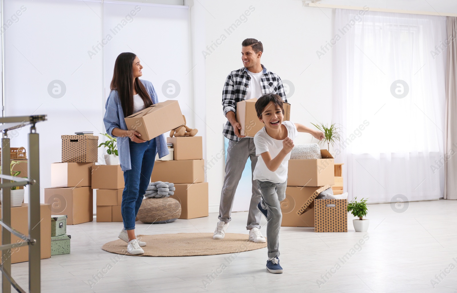 Photo of Happy family in room with cardboard boxes on moving day