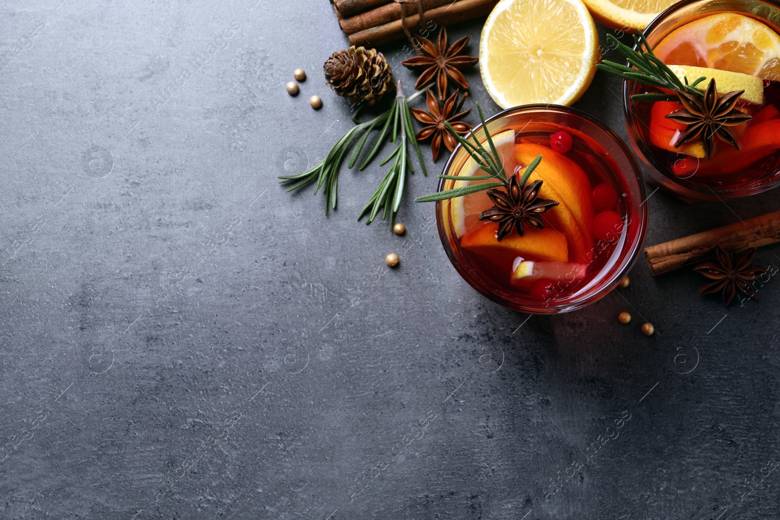 Photo of Delicious punch drink with cranberries, orange and spices on grey table, flat lay. Space for text