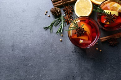 Photo of Delicious punch drink with cranberries, orange and spices on grey table, flat lay. Space for text