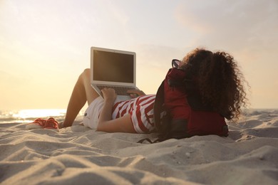 African American woman working on laptop at beach