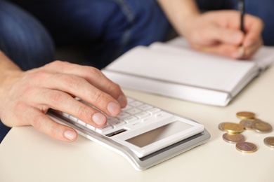 Photo of Man counting money with calculator at table, closeup