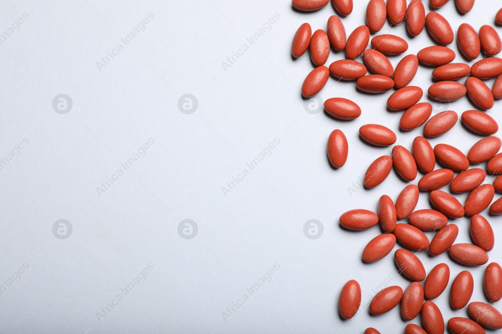 Photo of Red pills on white background, flat lay with space for text. Anemia treatment