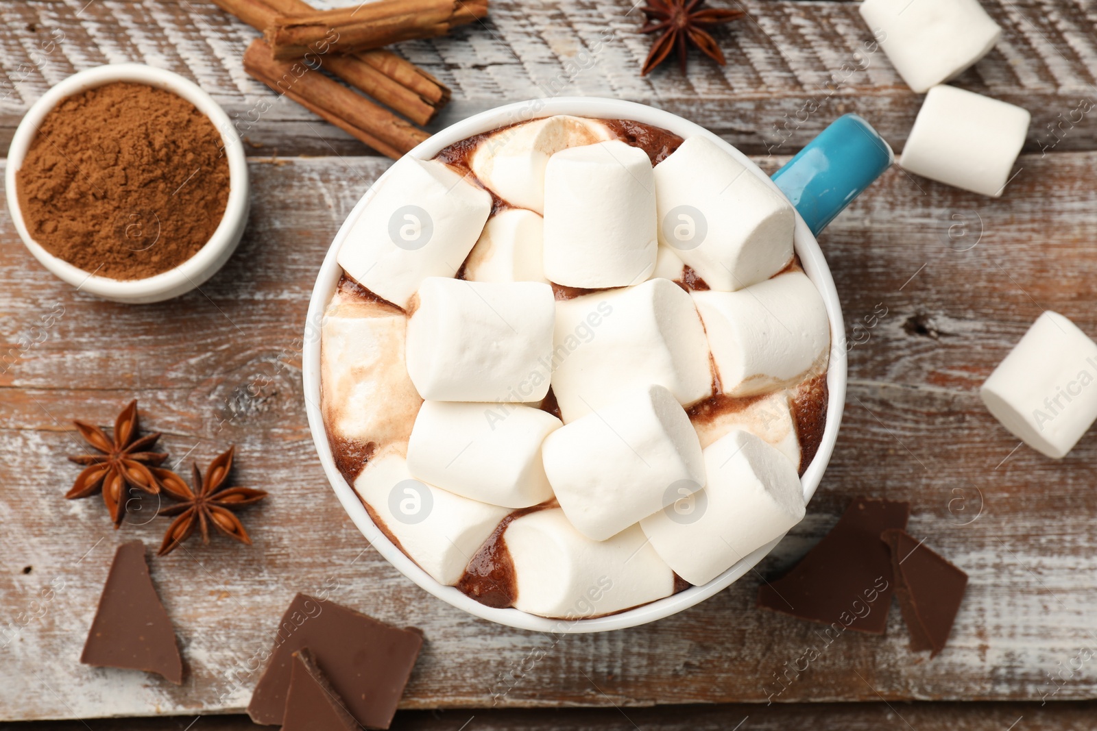 Photo of Tasty hot chocolate with marshmallows and ingredients on wooden table, flat lay