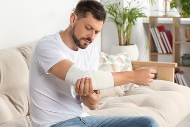 Photo of Man with arm wrapped in medical bandage at home