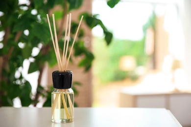 Photo of Aromatic reed air freshener on table indoors