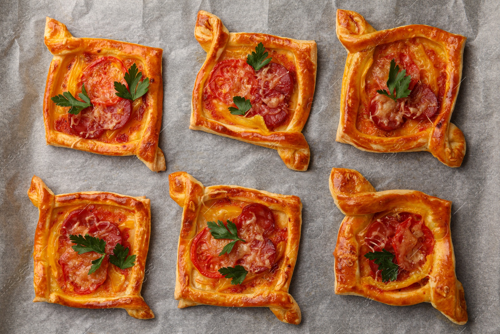 Photo of Fresh delicious puff pastry with tasty filling on parchment, top view