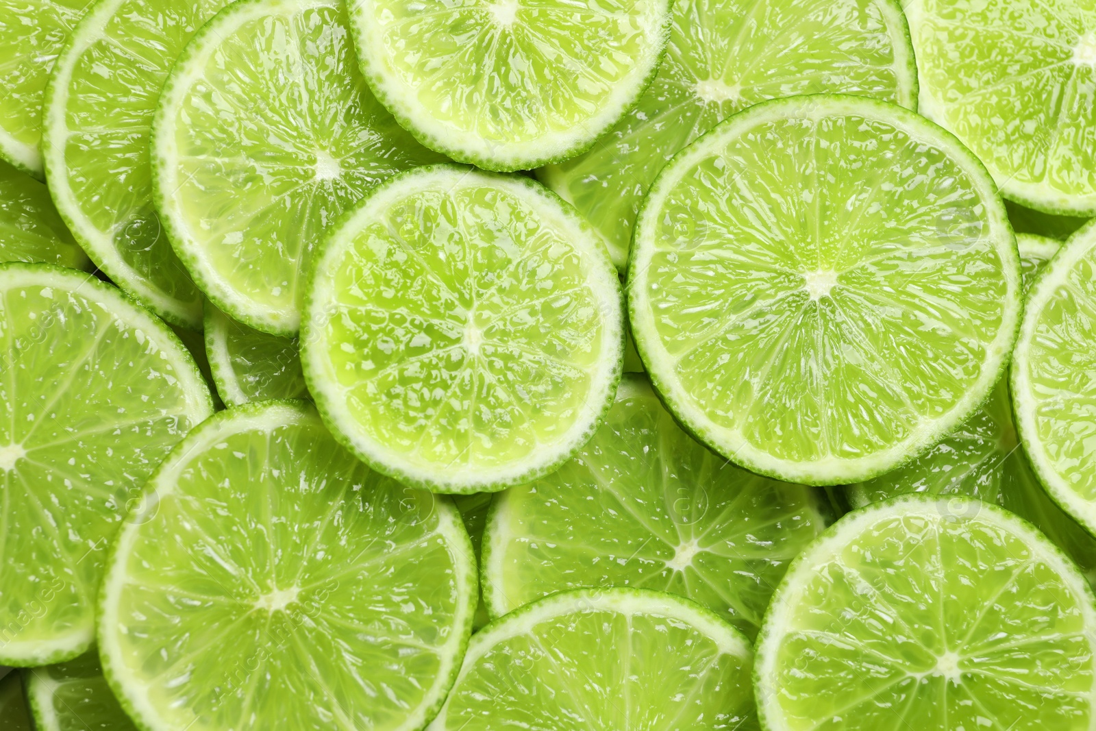 Photo of Fresh sliced ripe limes as background, top view