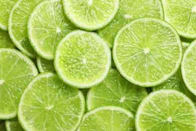 Photo of Fresh sliced ripe limes as background, top view