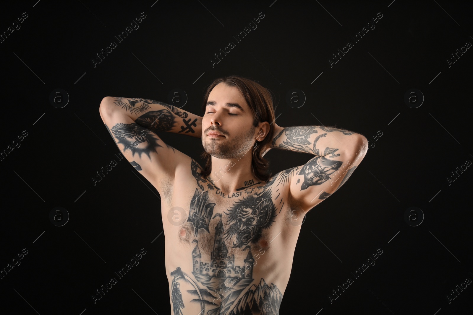 Photo of Young man with tattoos on body against black background