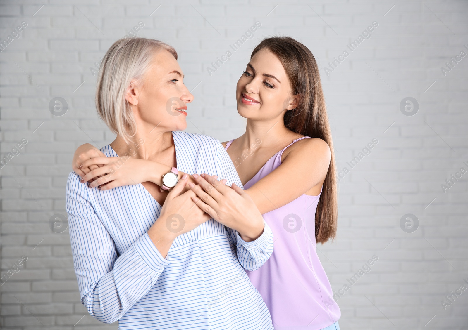 Photo of Portrait of young woman with her mature mother near brick wall