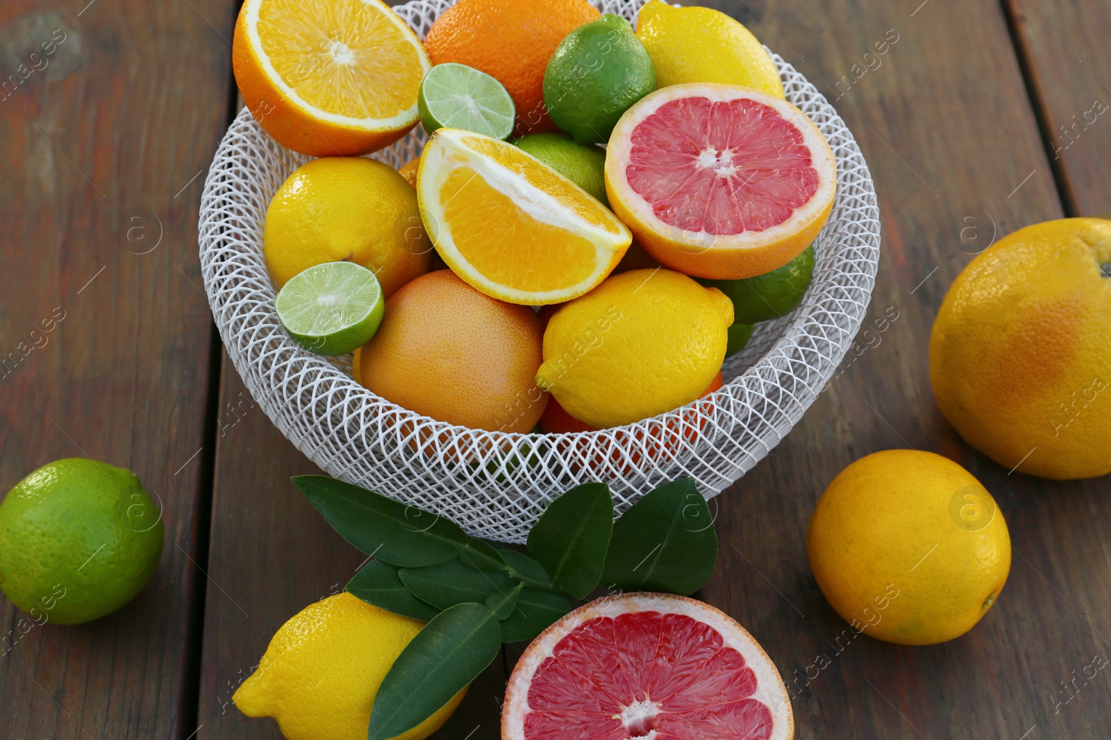 Photo of Different citrus fruits and leaves on wooden table