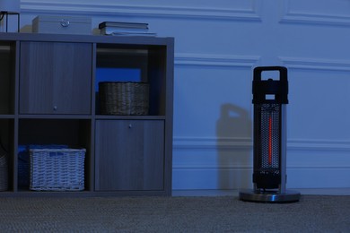 Photo of Electric infrared heater in dark room at night