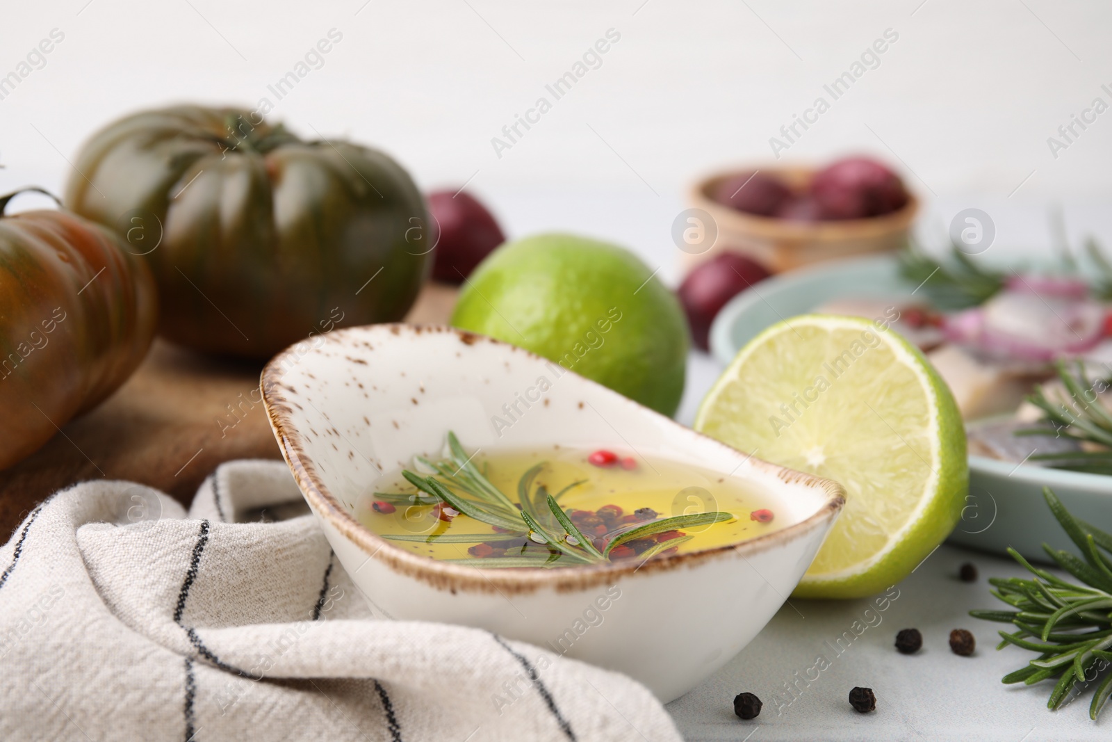 Photo of Tasty fish marinade with rosemary and products on light table, closeup