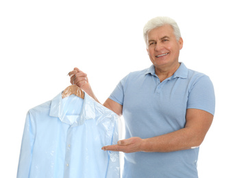 Photo of Senior man holding hanger with shirt in plastic bag on white background. Dry-cleaning service
