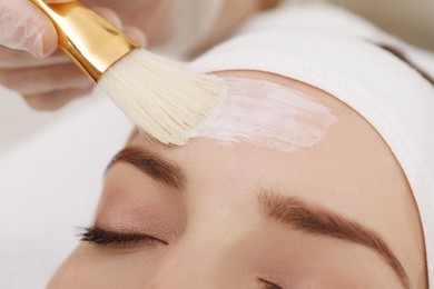 Photo of Young woman during face peeling procedure in salon, closeup