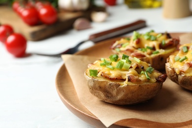 Photo of Plate of baked potatoes with cheese and bacon on table, closeup. Space for text