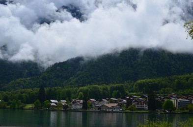 Photo of Picturesque view of beautiful village on lake shore near mountains