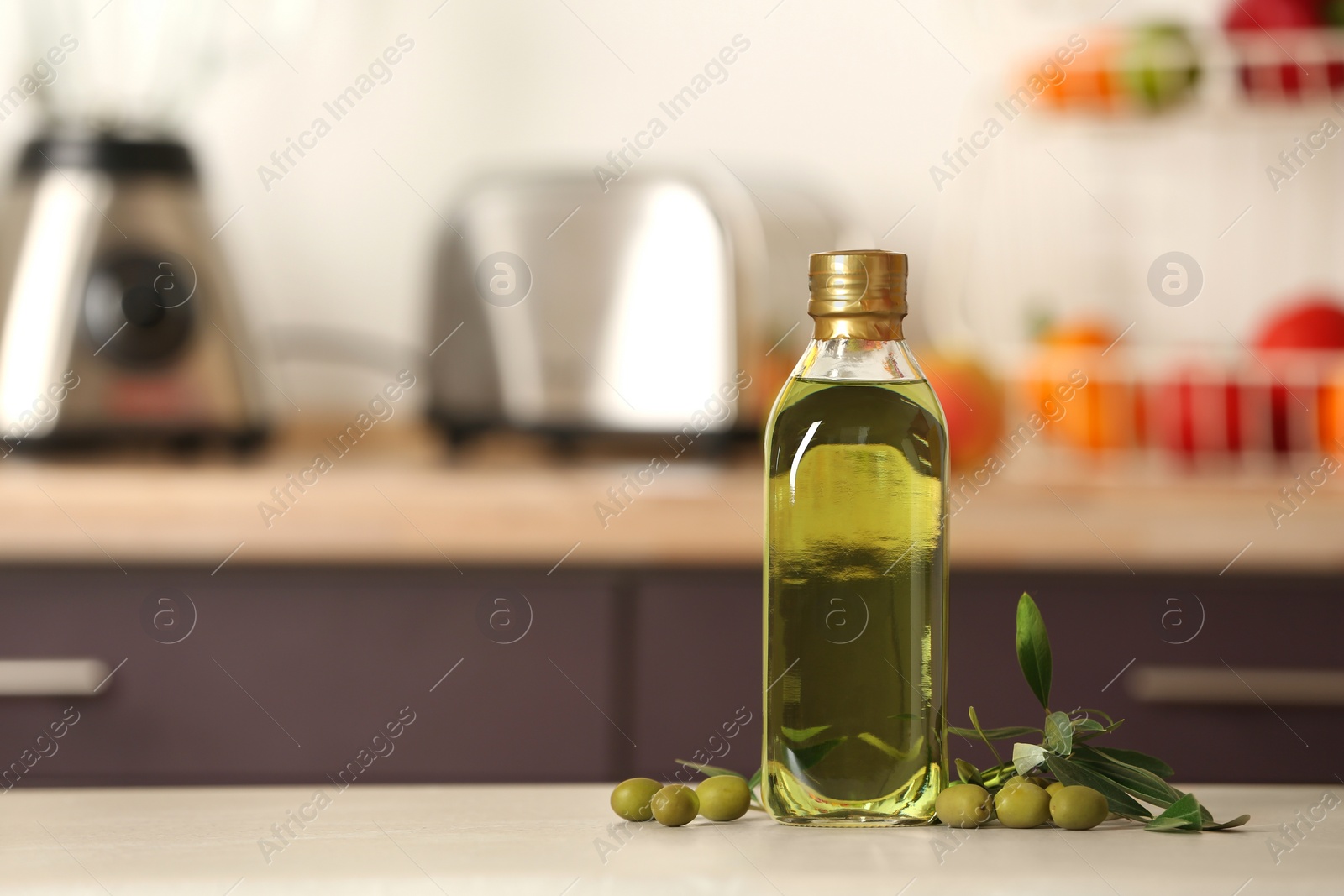 Photo of Bottle of olive oil on table against blurred background. Space for text