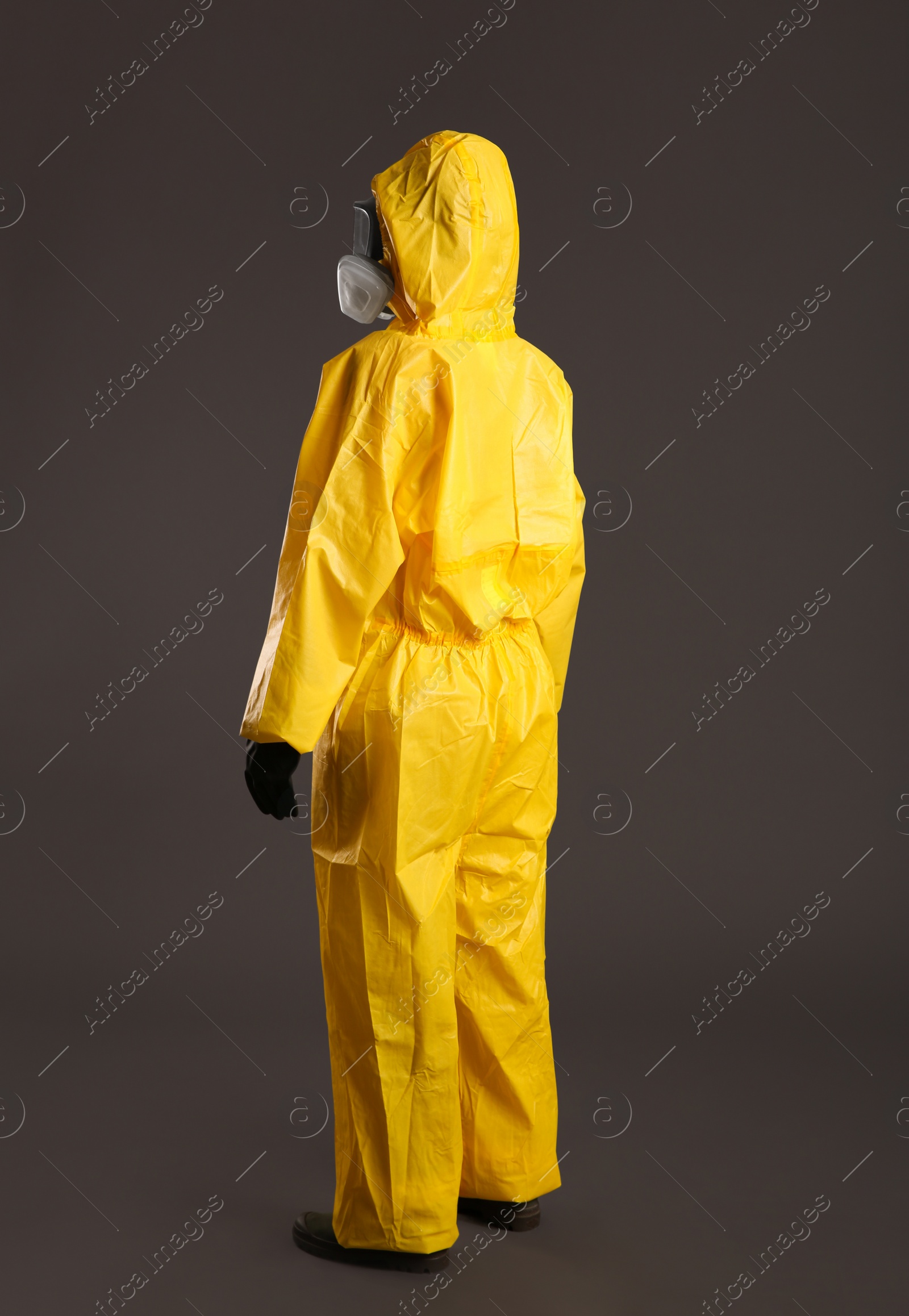Photo of Woman wearing chemical protective suit on grey background. Virus research