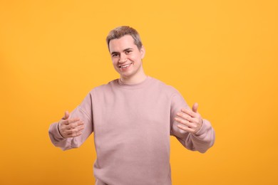 Photo of Happy man inviting to come in against orange background