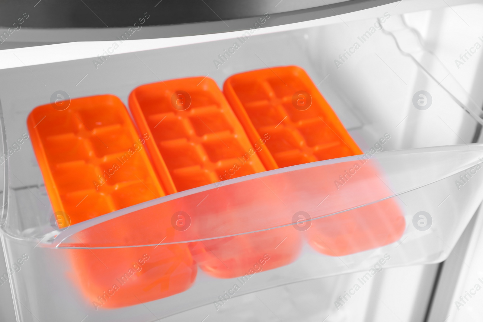 Photo of Orange plastic ice cube trays in fridge