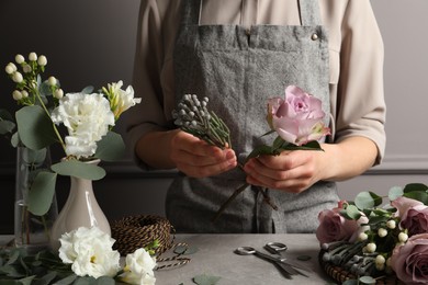Photo of Florist creating beautiful bouquet at grey table, closeup