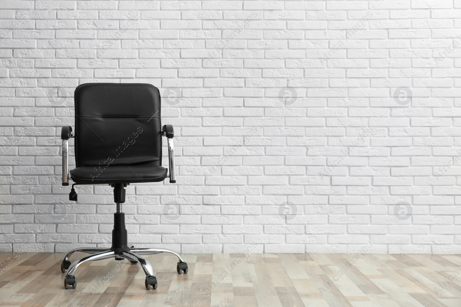 Photo of Comfortable office chair near white brick wall indoors. Space for text