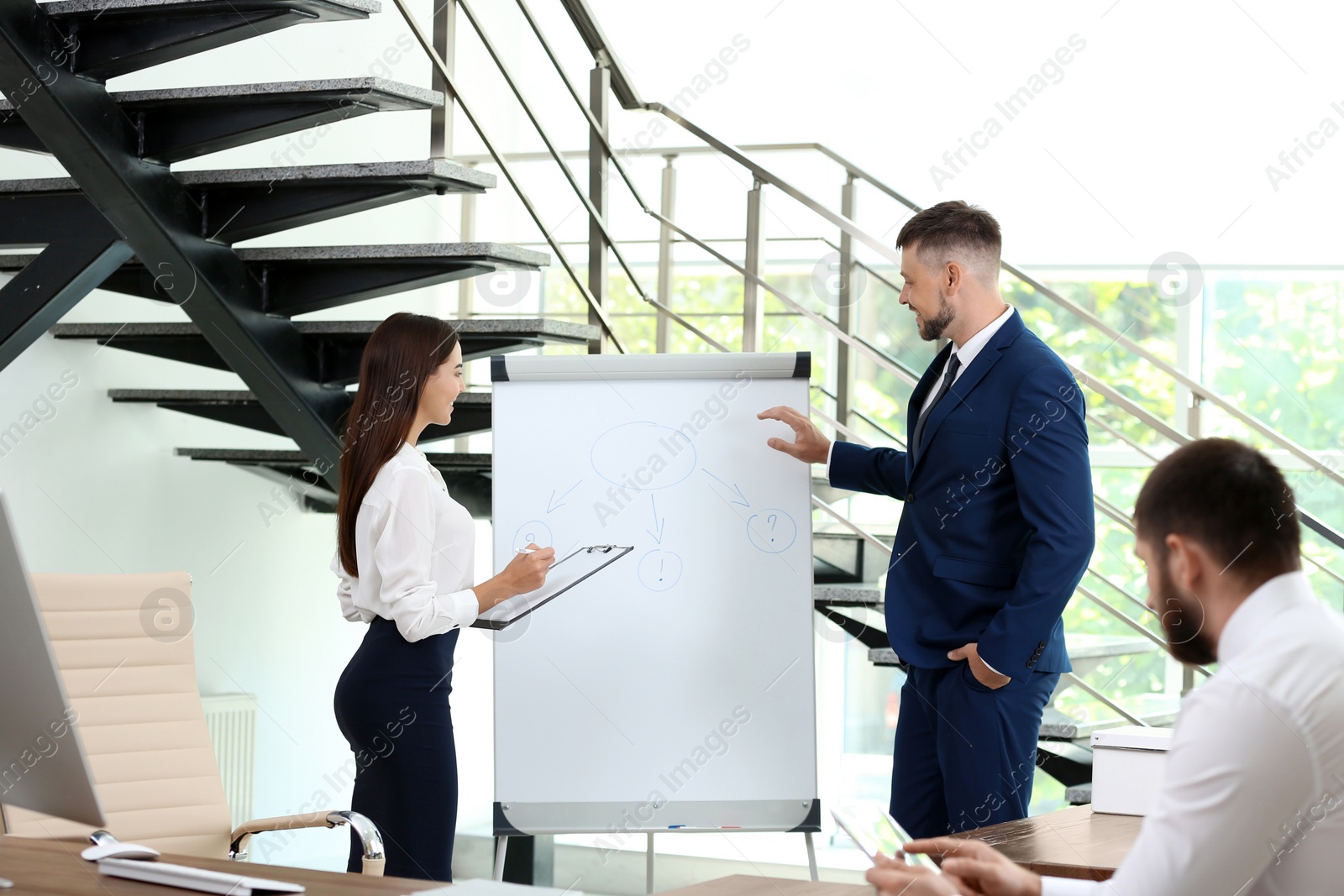 Photo of Man helping his colleague to give presentation on meeting in office