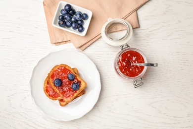 Photo of Toasts with jam and berries on wooden background, top view