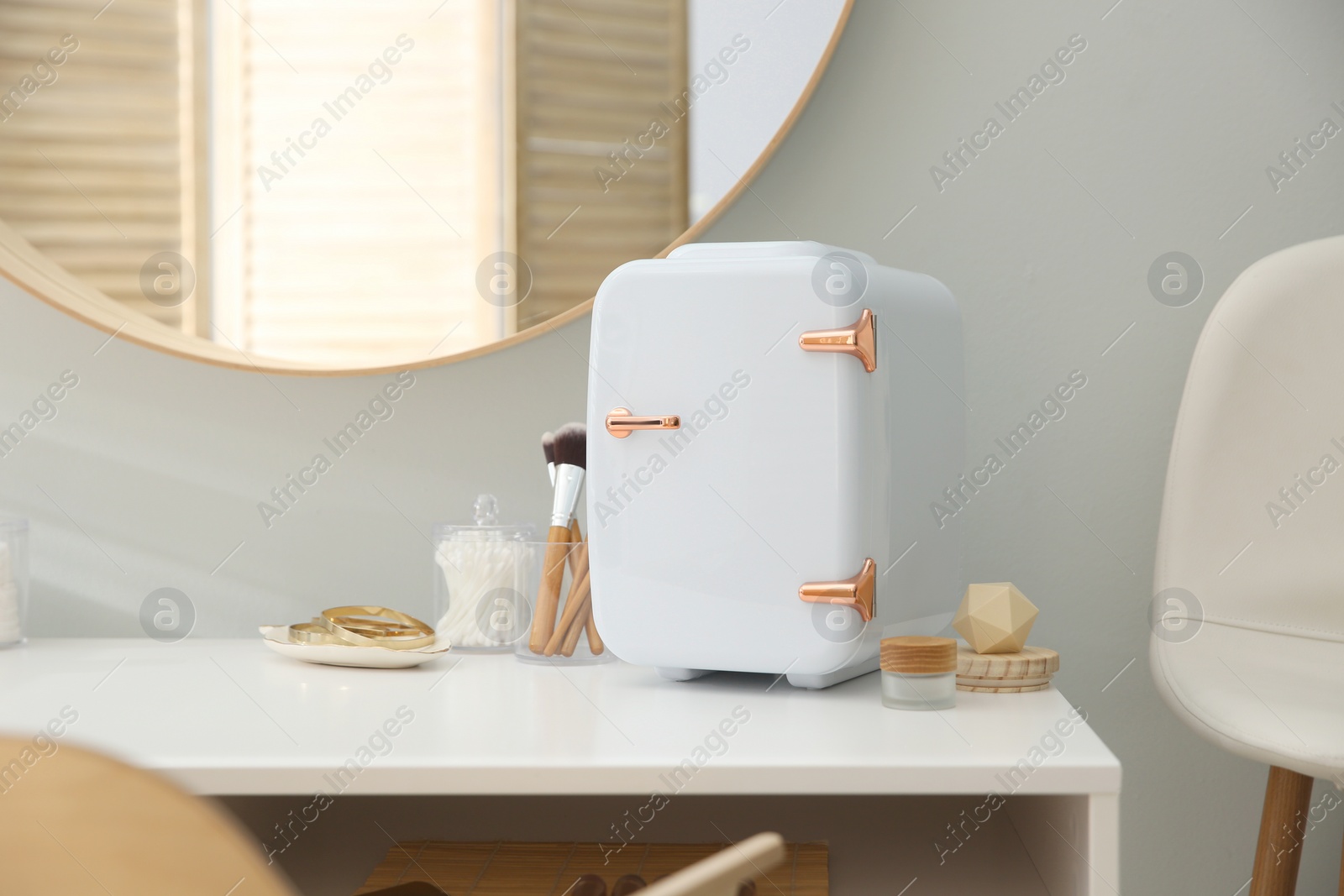 Photo of Cosmetics refrigerator and skin care products on white vanity table indoors