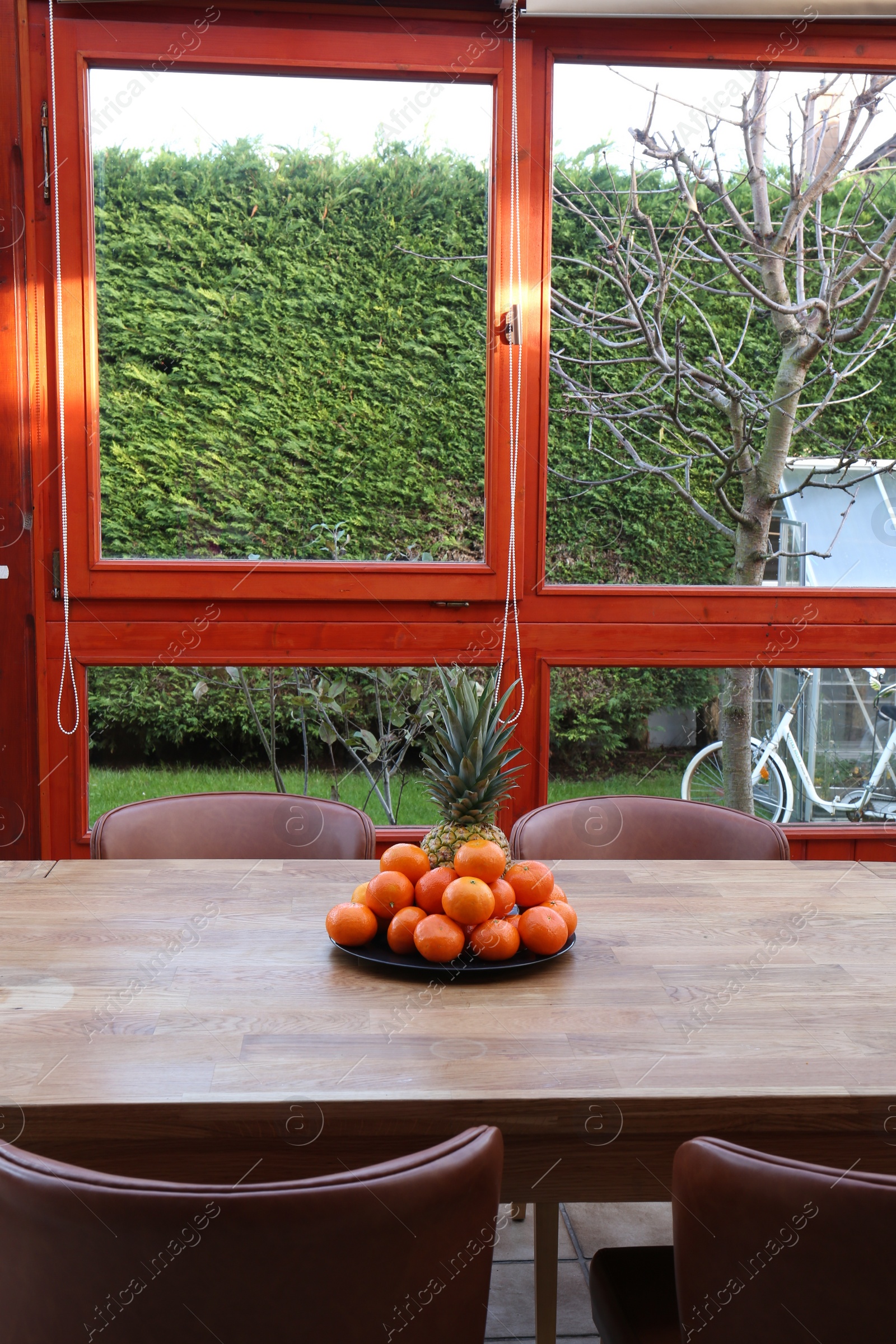 Photo of Fresh tangerines and pineapple on wooden table indoors