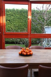 Fresh tangerines and pineapple on wooden table indoors