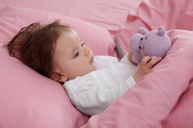Cute little baby with toy on bed