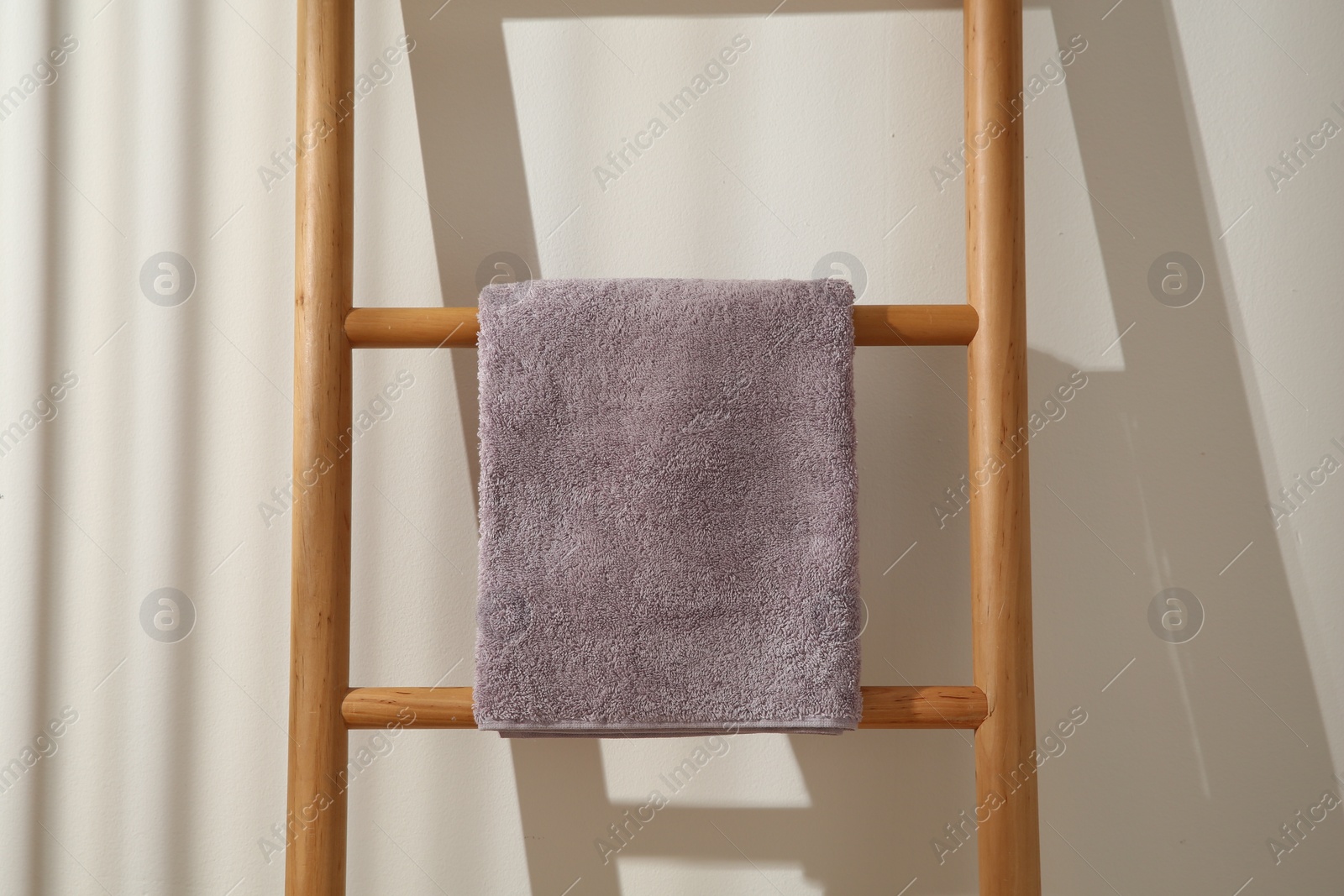 Photo of Violet towel hanging on wooden ladder indoors