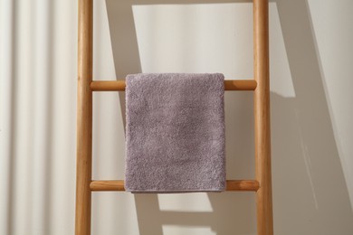 Violet towel hanging on wooden ladder indoors