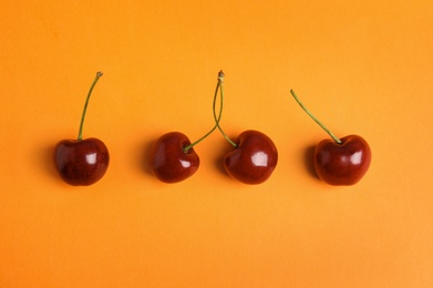 Photo of Juicy sweet cherries on orange background, top view