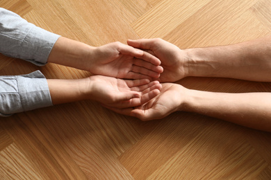 Photo of Young people holding hands on wooden background, top view. Happy family