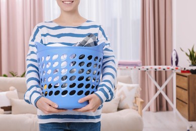 Woman with basket full of laundry at home, closeup