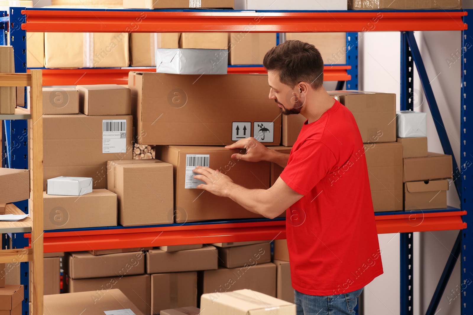 Photo of Post office worker near rack with parcels indoors