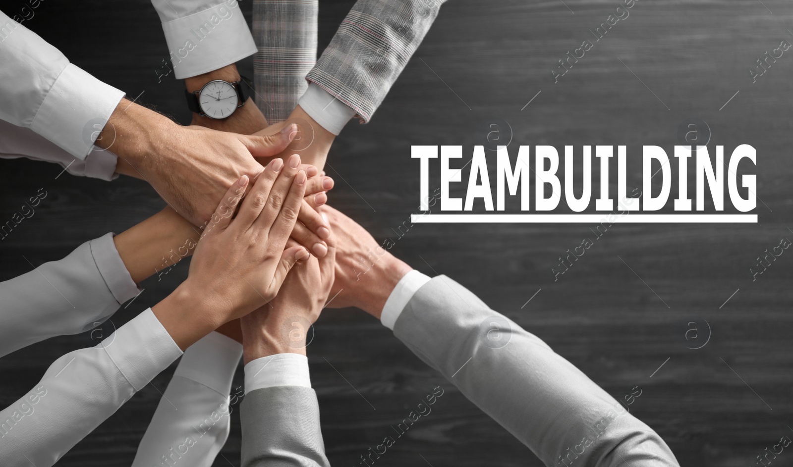 Image of People holding hands together over grey wooden background, top view. Team building