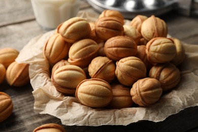 Photo of Bowl of delicious nut shaped cookies on wooden table, closeup