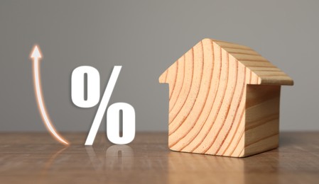 Image of Mortgage rate. Wooden model of house, arrow and percent sign on table, banner design