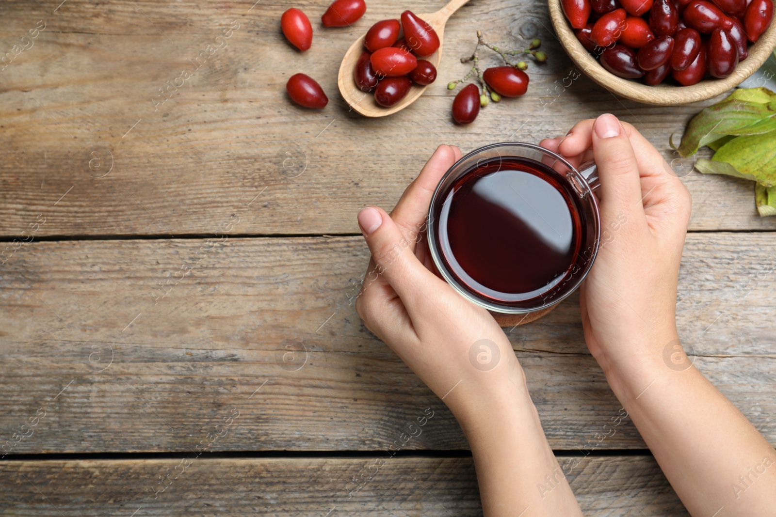 Photo of Woman with cup of fresh dogwood tea at wooden table, top view. Space for text