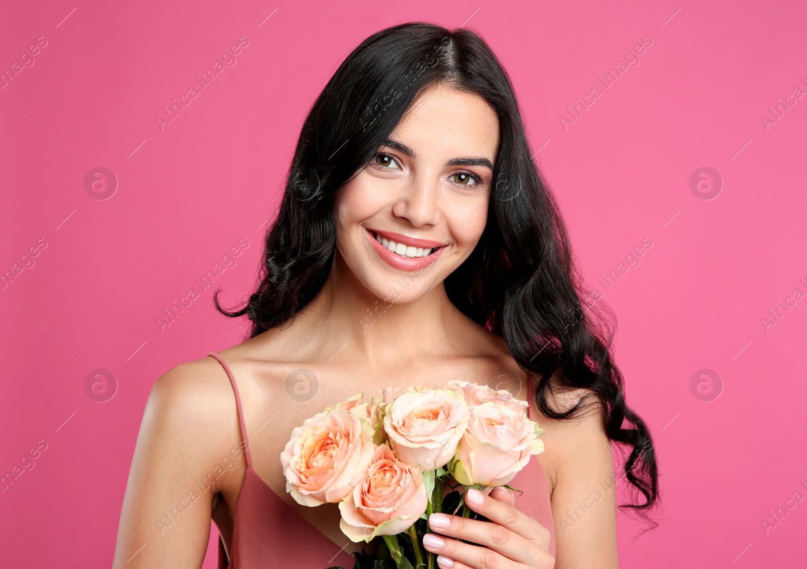 Photo of Portrait of smiling woman with beautiful bouquet on pink background